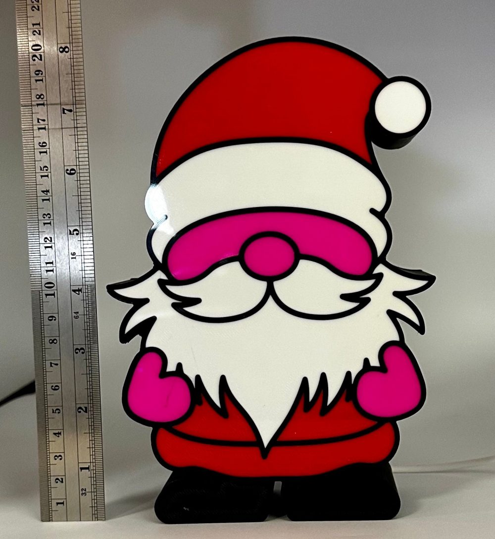 Alt text: Lighted Christmas gnome decoration, shaped like a Santa with pink gloves, standing next to a ruler for scale.