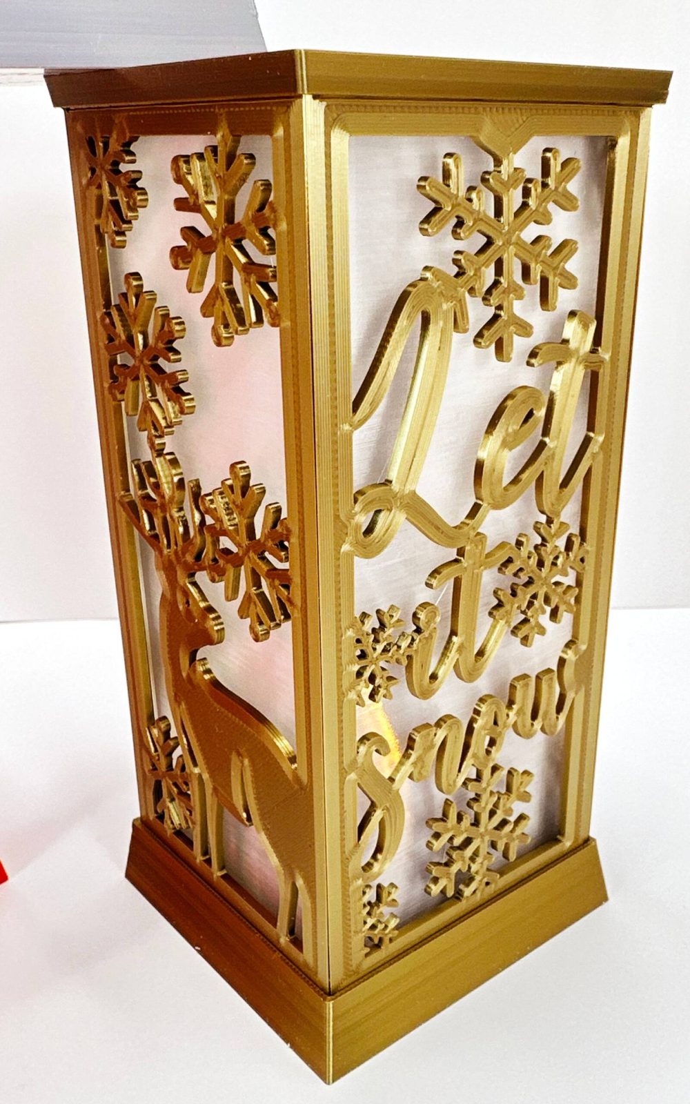 Decorative golden Christmas LED candle lantern with intricate snowflake and reindeer cutouts.