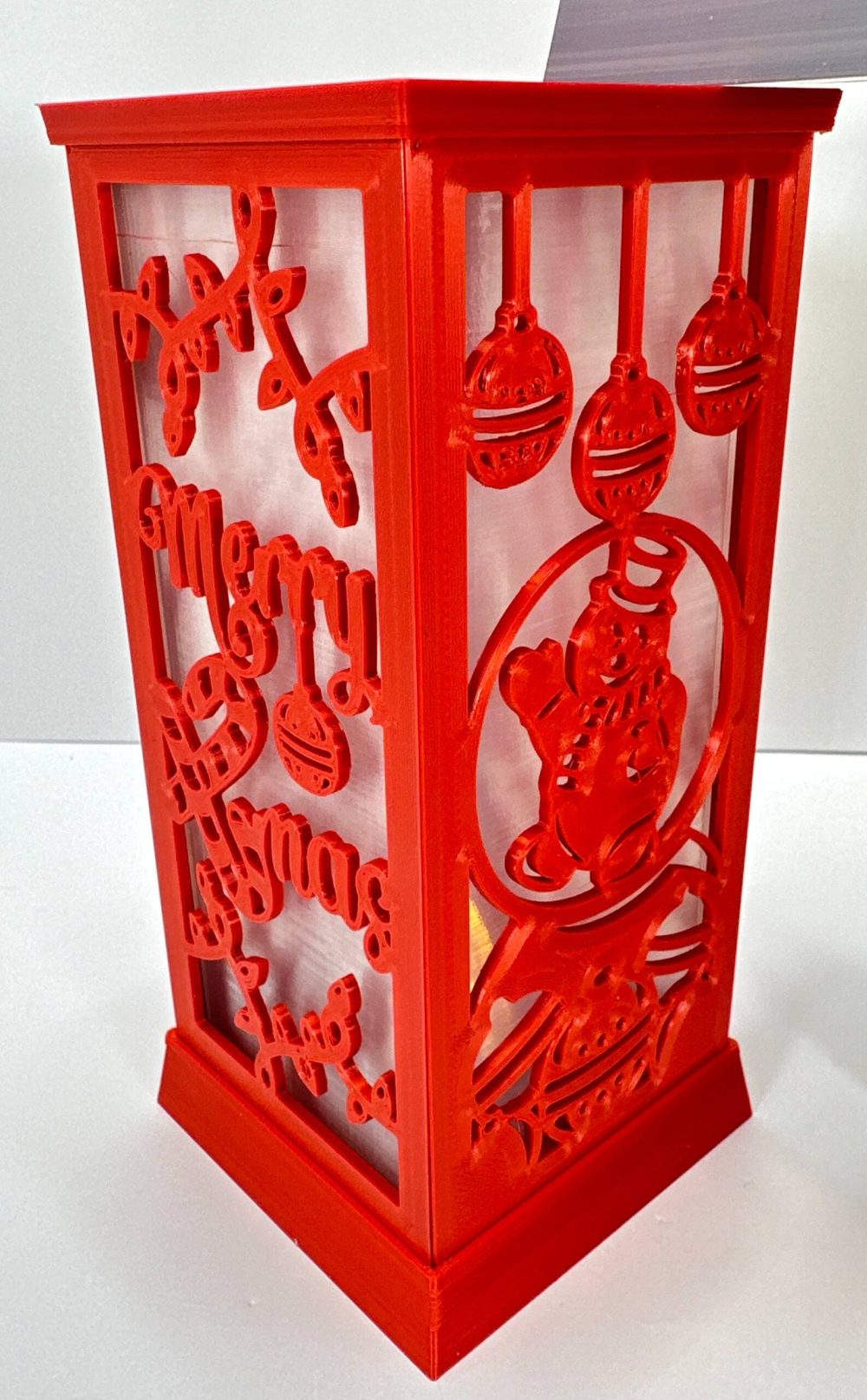 Red Christmas LED candle lantern with cut-out festive designs and hanging ornaments.