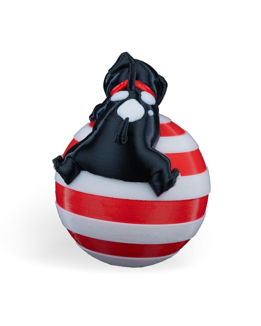 Handcrafted Sleeping Dog Christmas Ornament with a black puppy on a red and white striped ball. Festive holiday decor.