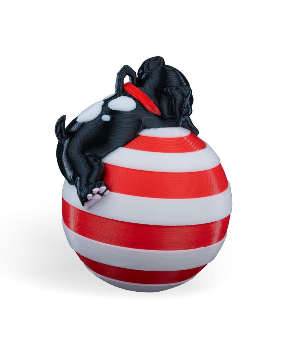 Handcrafted Christmas ornament featuring a sleeping black puppy on a red and white striped bauble.