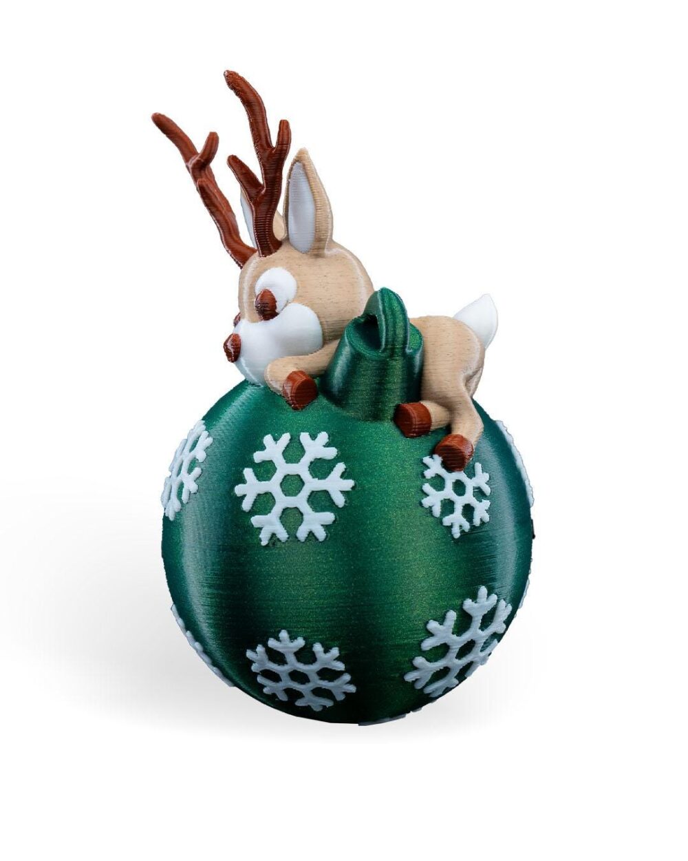 Handmade lying reindeer Christmas ornament on a green ball with snowflakes; unique holiday decoration.