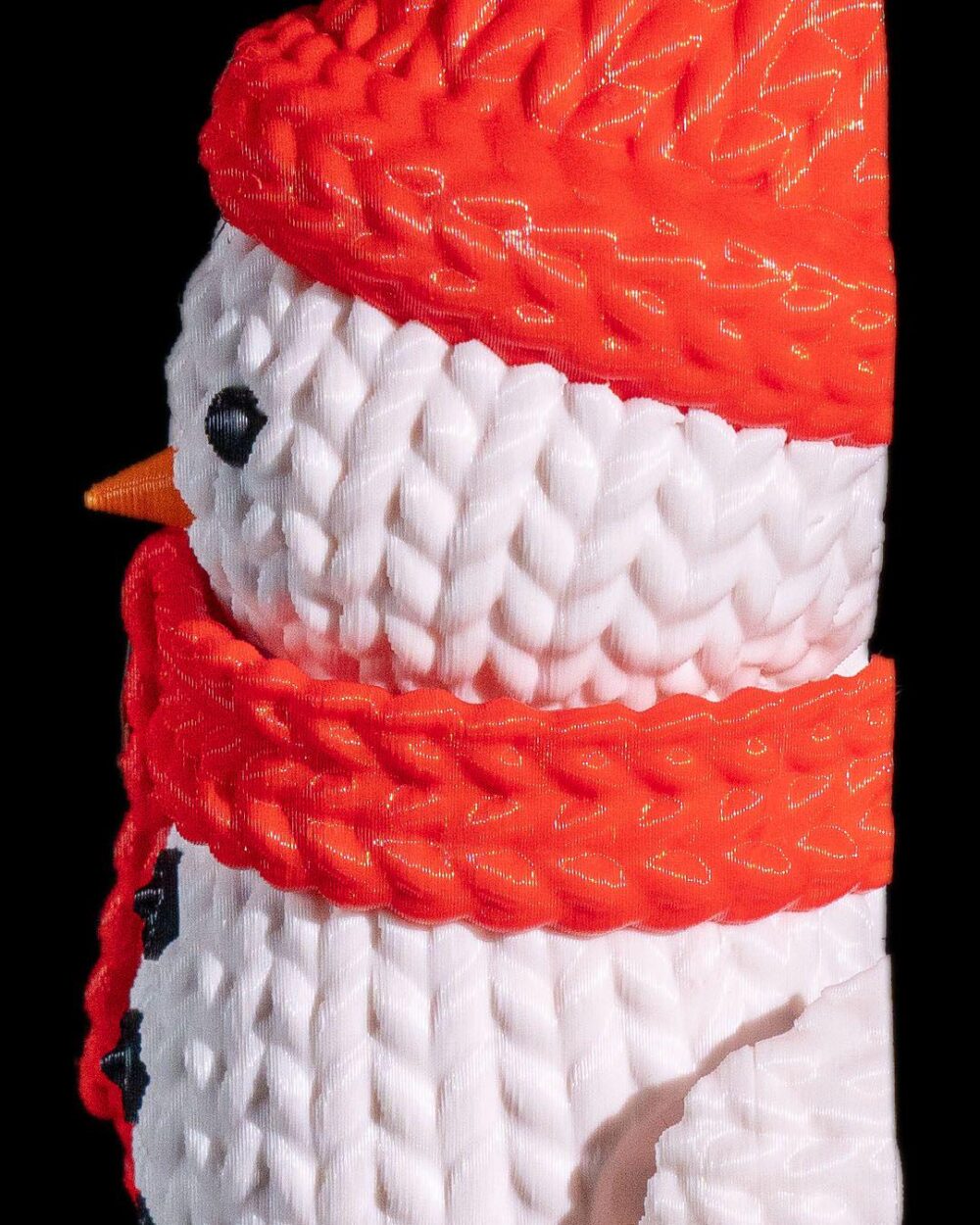 Close-up of a 3D printed snowman with an orange hat and scarf, featuring black buttons and eyes on a product page for Christmas decor.