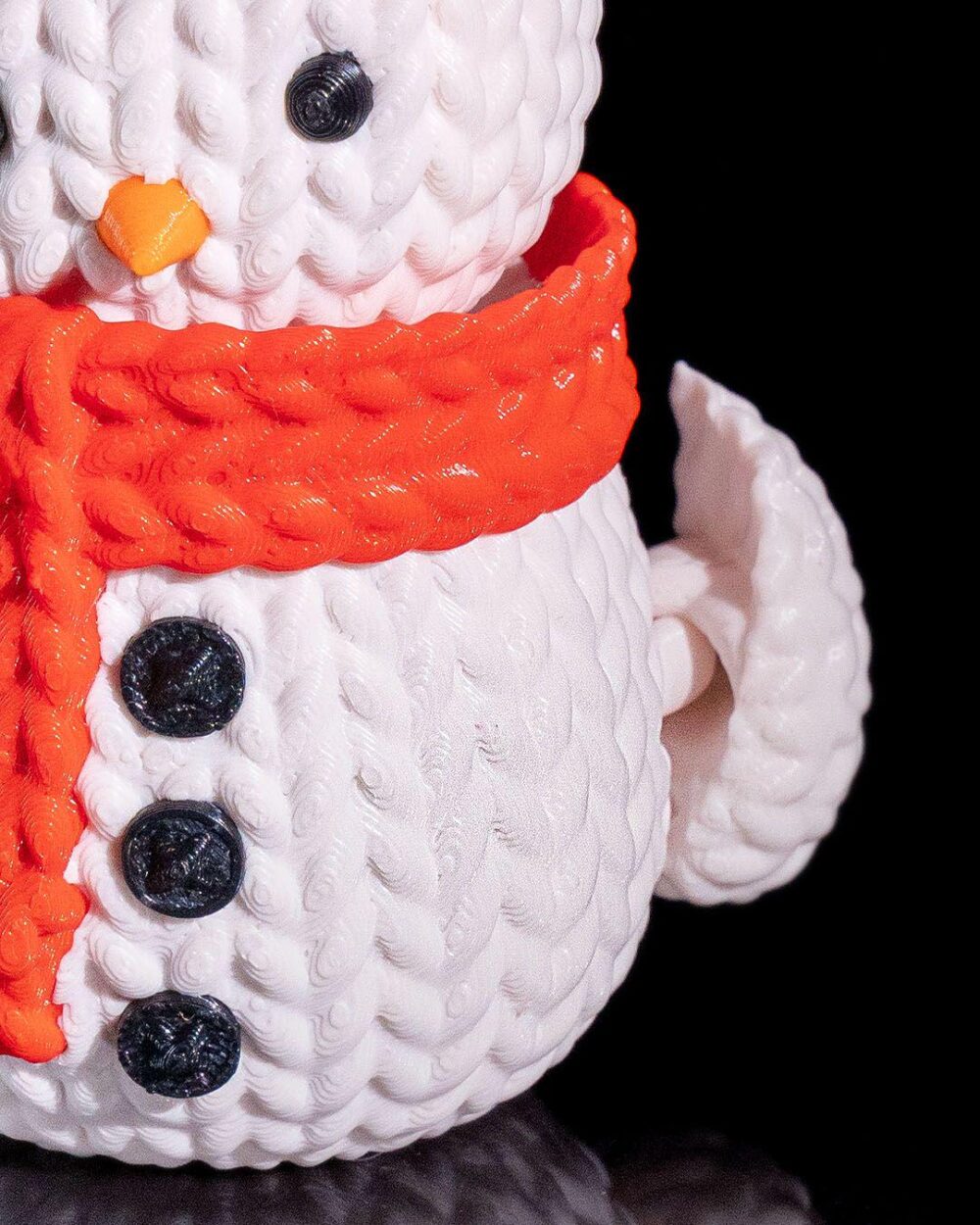 Close-up of a Charming 3D Printed Snowman Decoration, showcasing orange scarf and black button details on white textured body.